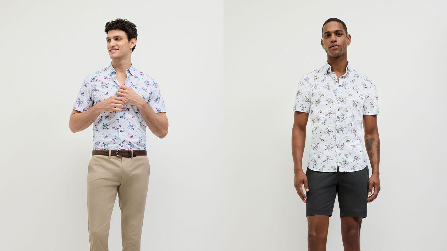Men wearing the POLITIX Bouquet Floral short sleeve shirt in white with magenta and blue floral print, styled with tan chinos and black shorts.