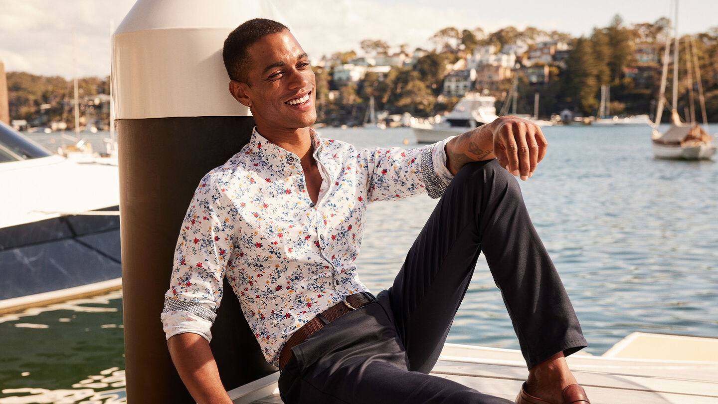Model in POLITIX Spring Summer 2025 fusion floral long sleeve shirt with navy chinos, styled by the marina – statement men’s shirt for parties and summer events