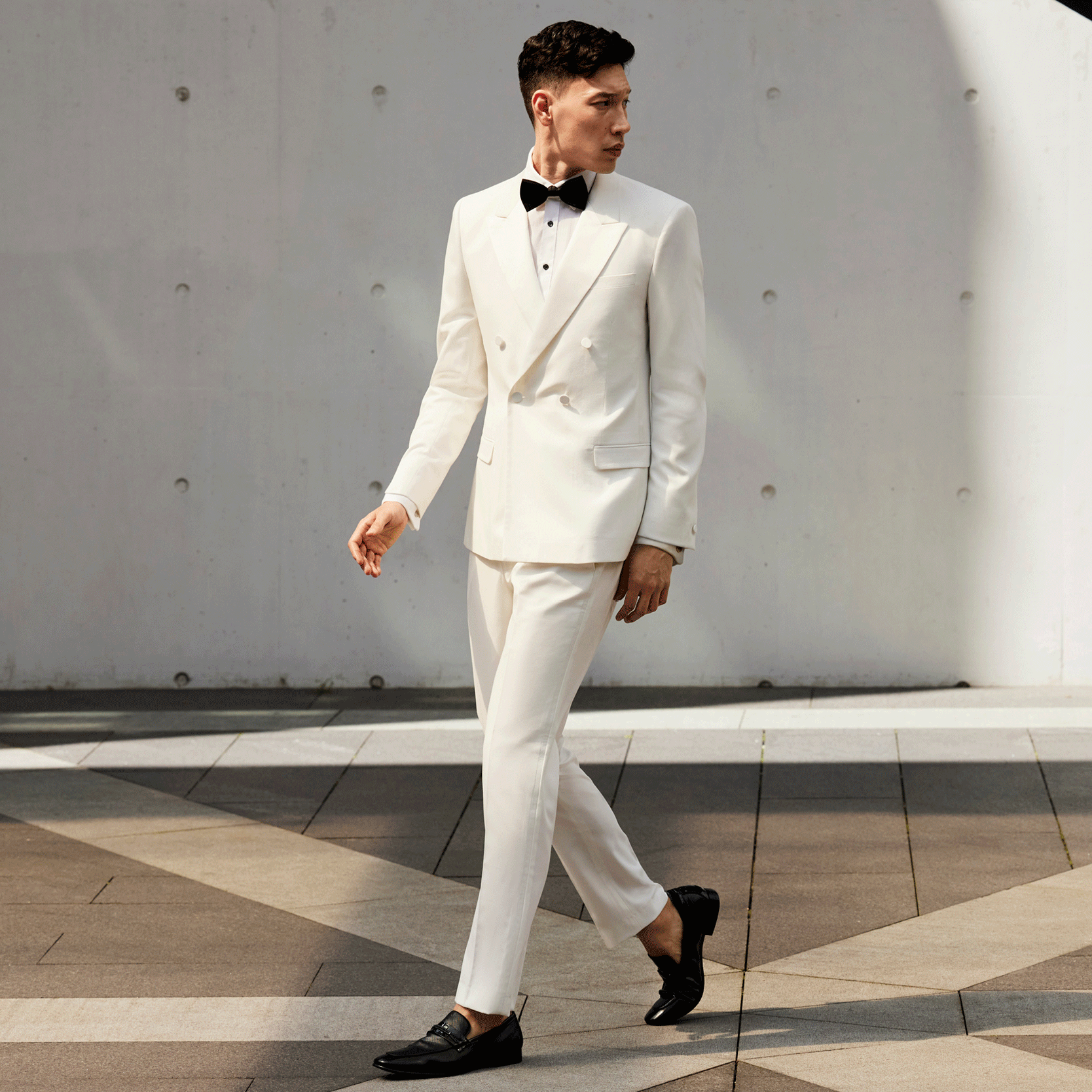Double the attention Model wearing POLITIX Double Breasted Ivory Suit standing still in front of a moving crowd
