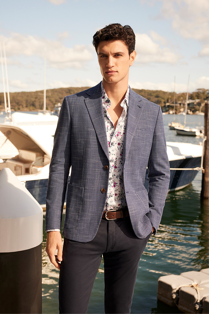 Model in POLITIX Spring Summer 2025 navy Prince of Wales check blazer paired with floral shirt and chinos, styled by the marina – smart casual menswear for event season.