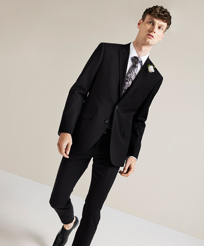 Model wearing black POLITIX regular fit suit, white shirt and paisley tie standing in front of a white background