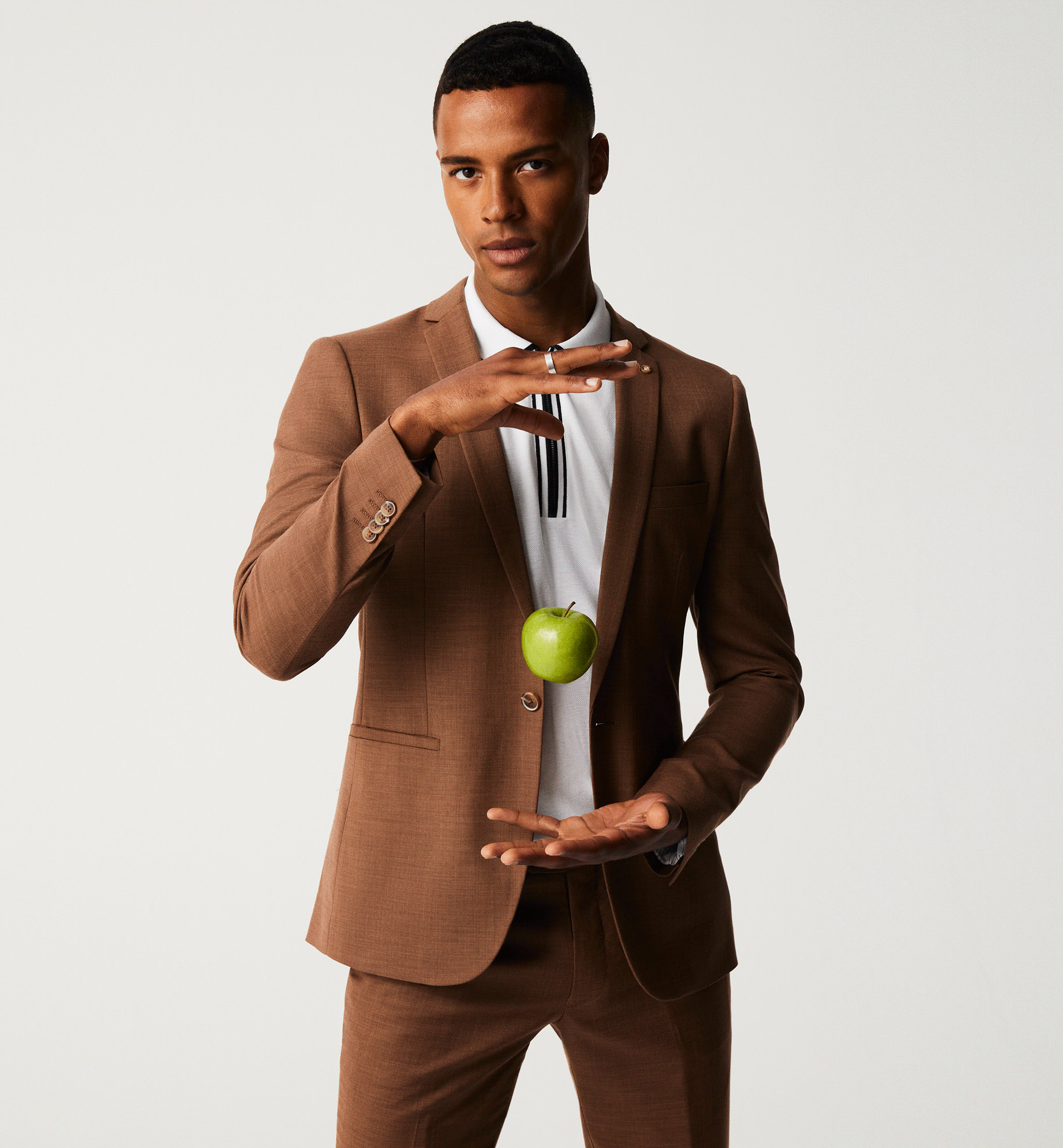 Create Some Magic Model wearing brown suit and holding levitating apple