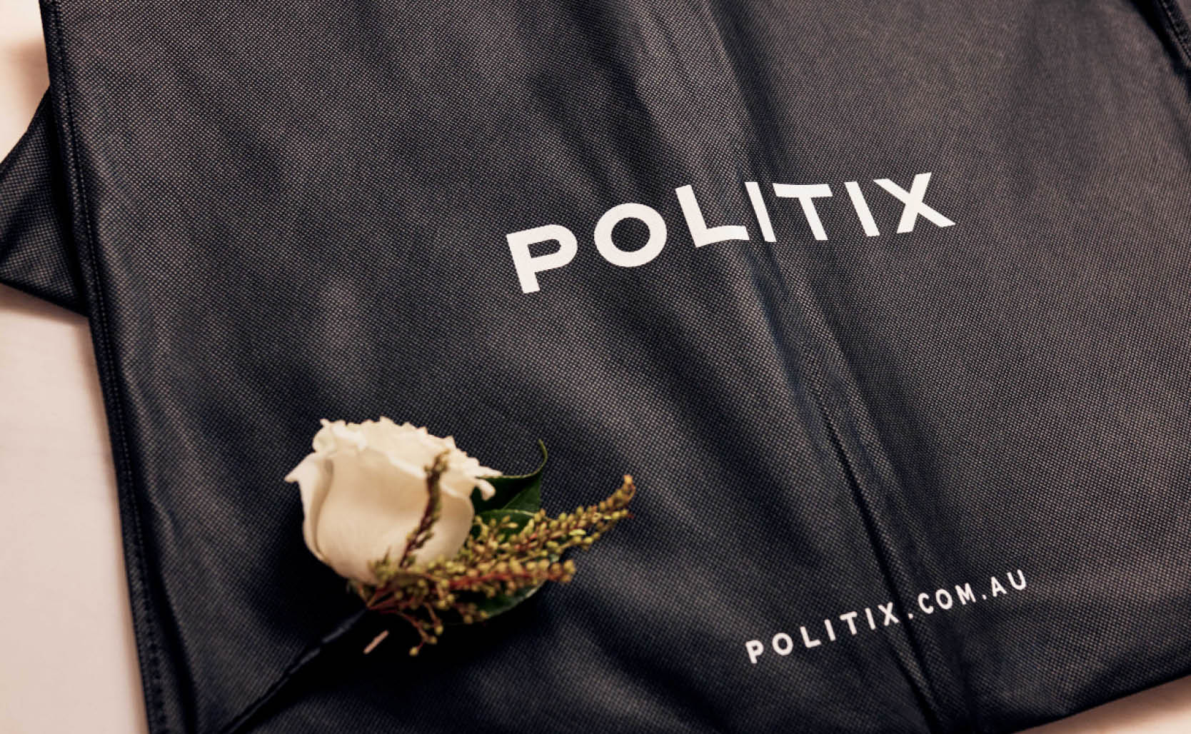Politix suit bag flatlayed with corsage