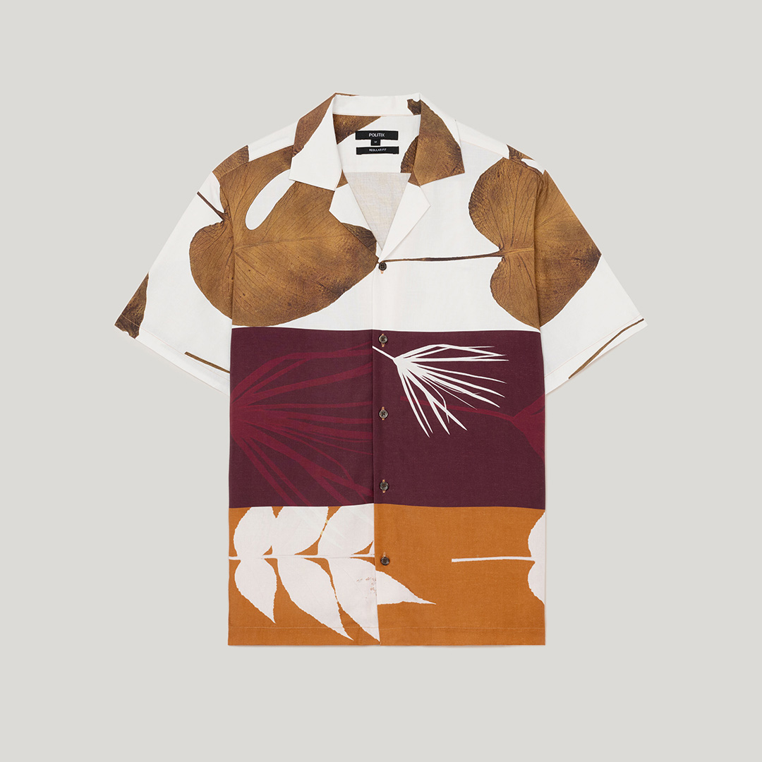 Thanasi Kokkinakis wearing a nMen’s fossil print short sleeve shirt in earthy brown, maroon, and ochre panel design.avy POLITIX suit with a white shirt, floral tie, and matching pocket square against a green backdrop. Text overlay reads ‘Rule 5: Pocket Square,’ highlighting how small details add polish and personality to spring tailoring.