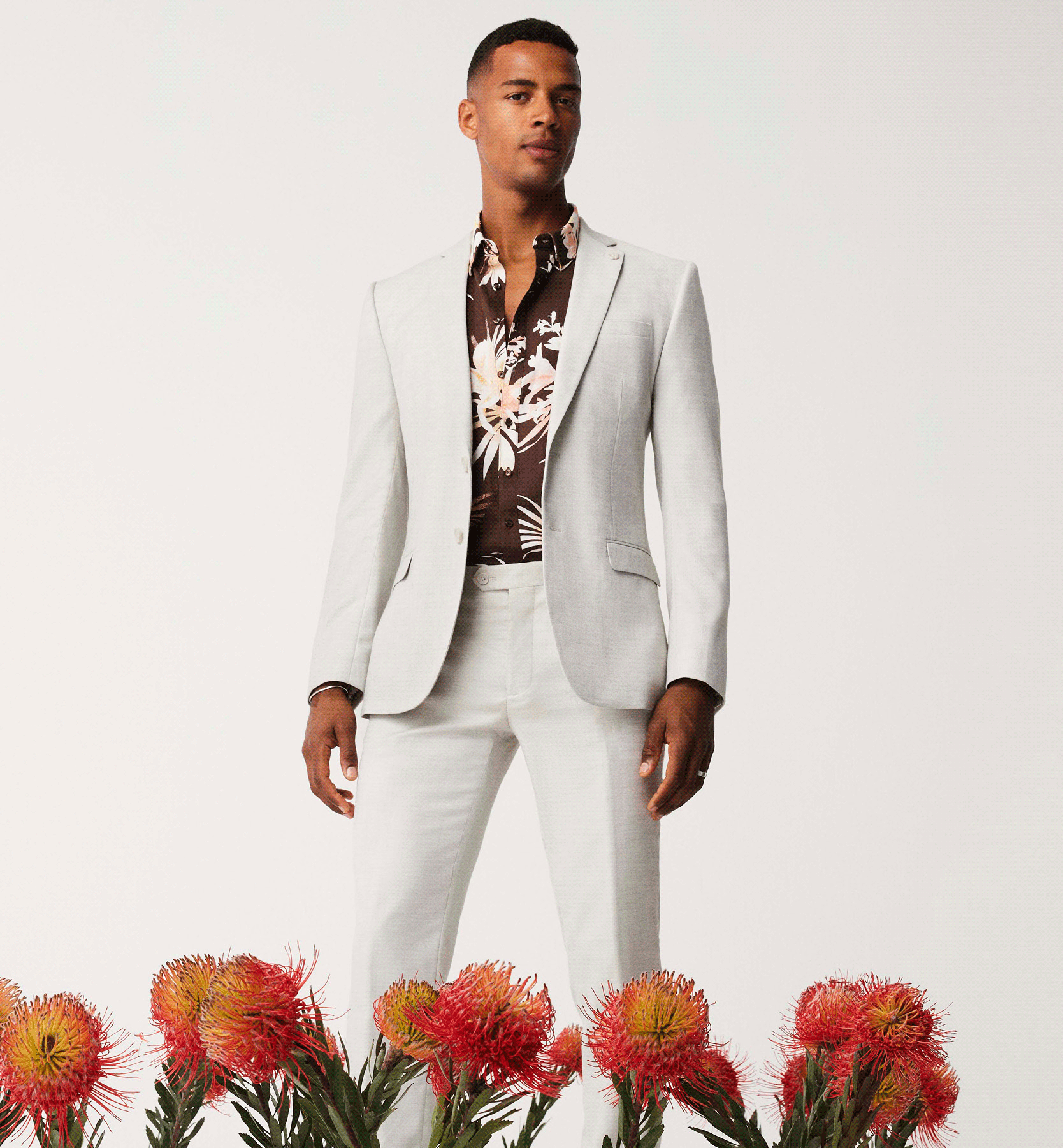 Embrace Florals Model wearing Grey POLITIX ssuit and floral shirt with fllower decorations