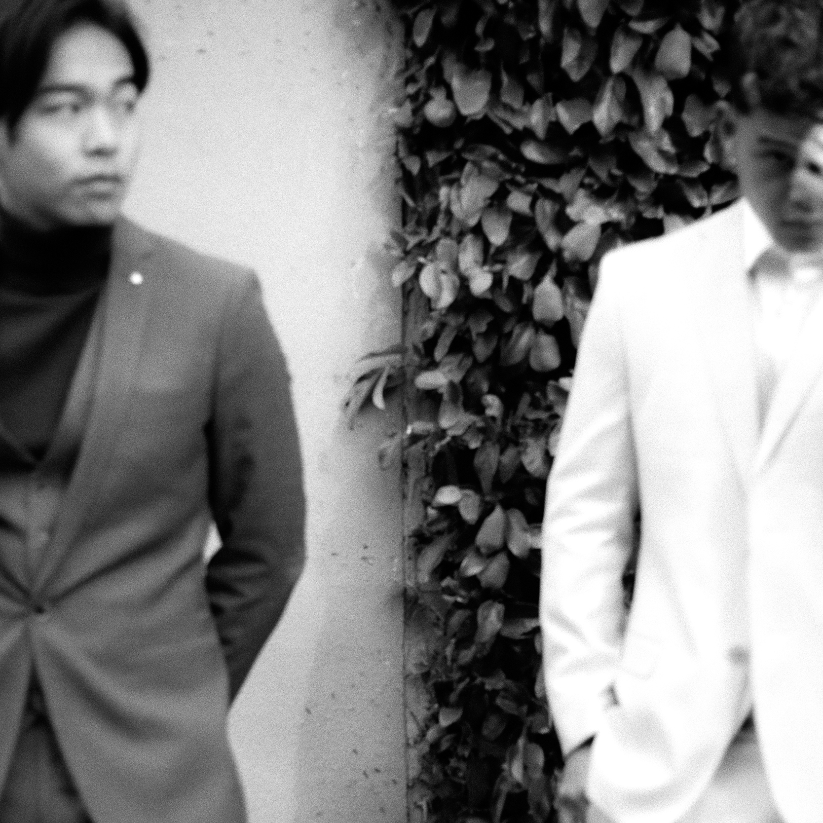 Black and white image og Mike and Nathan wearing POLITIX suits in front of concrete and leafy background